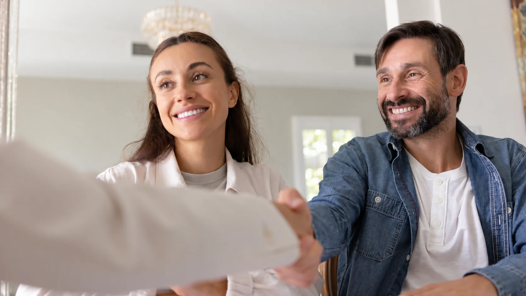 A smiling couple handshakes a specialist while discussing HVAC financing Washington plans.