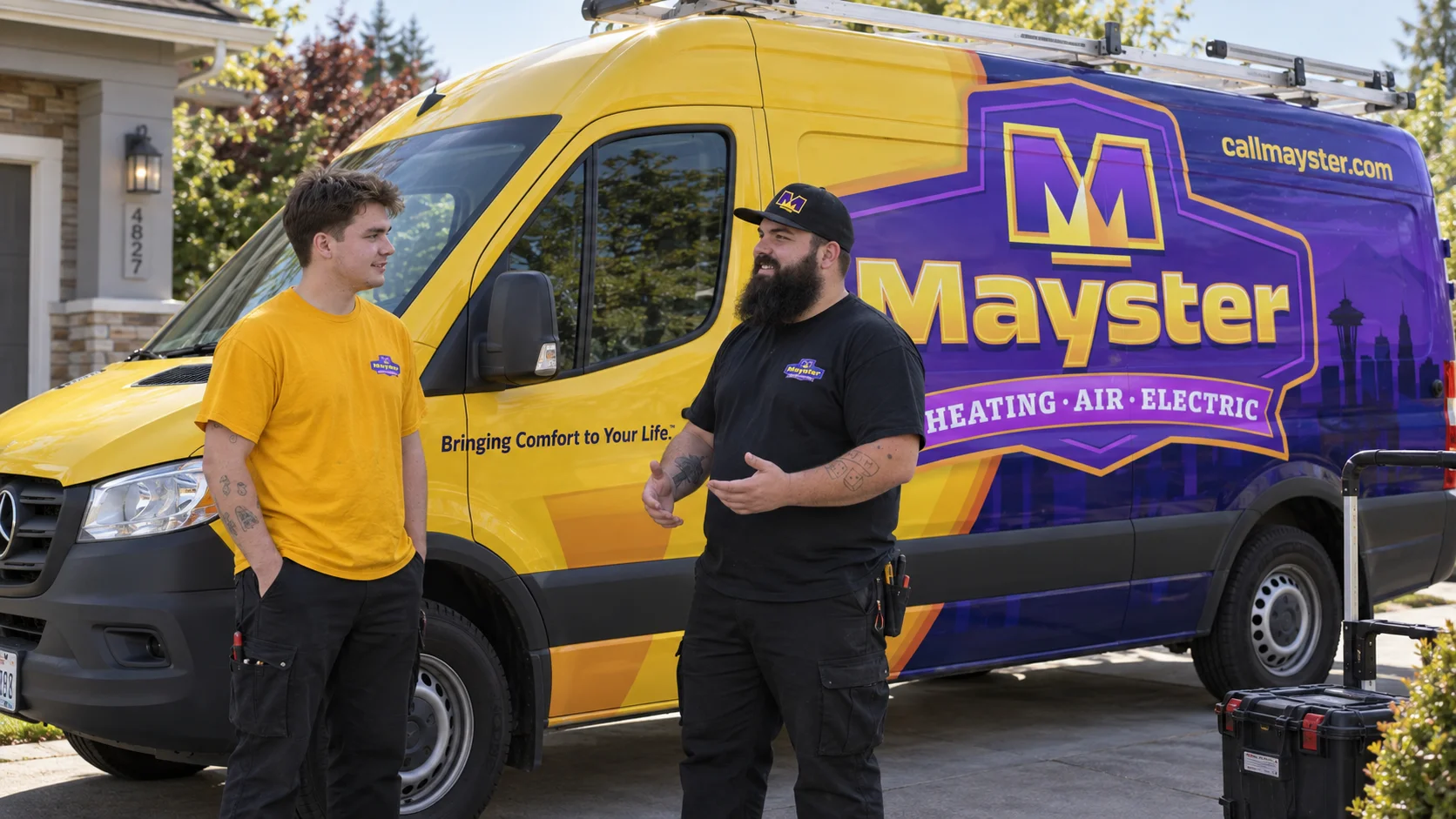 Two technicians stand and talk next to a large, branded Mayster service van in a residential driveway.