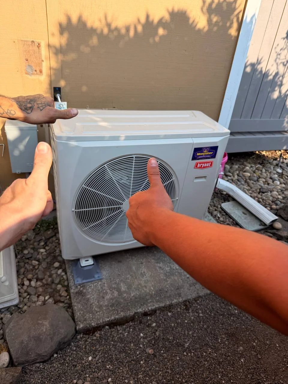 Three hands giving thumbs up in front of a newly installed HVAC unit from Heat Pump Services Greater Puget Sound.