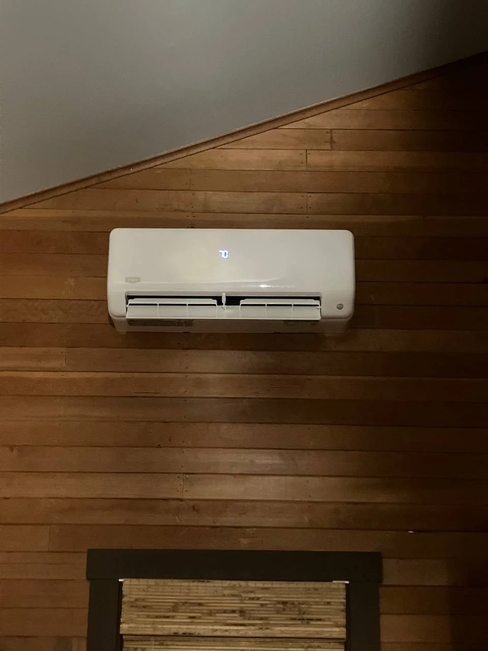 Modern wall-mounted AC unit operating on a wood accent wall via Mini Split Services Greater Puget Sound.