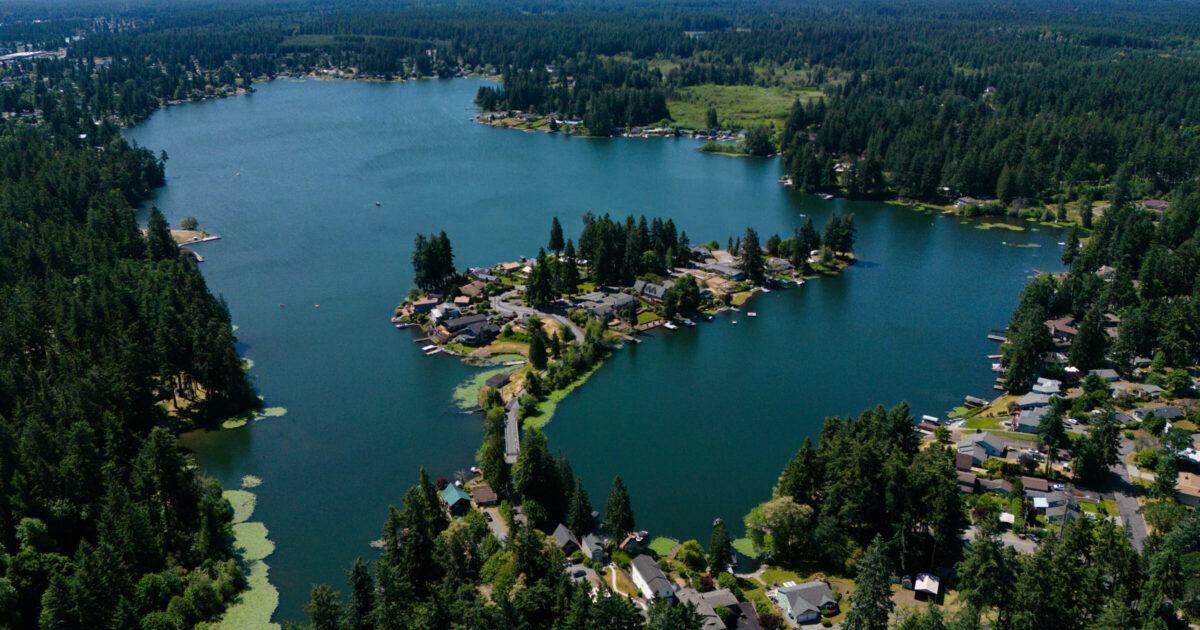 Aerial view of Spanaway Lake surrounded by evergreen trees, where Mayster provides HVAC services in Spanaway WA for local homes