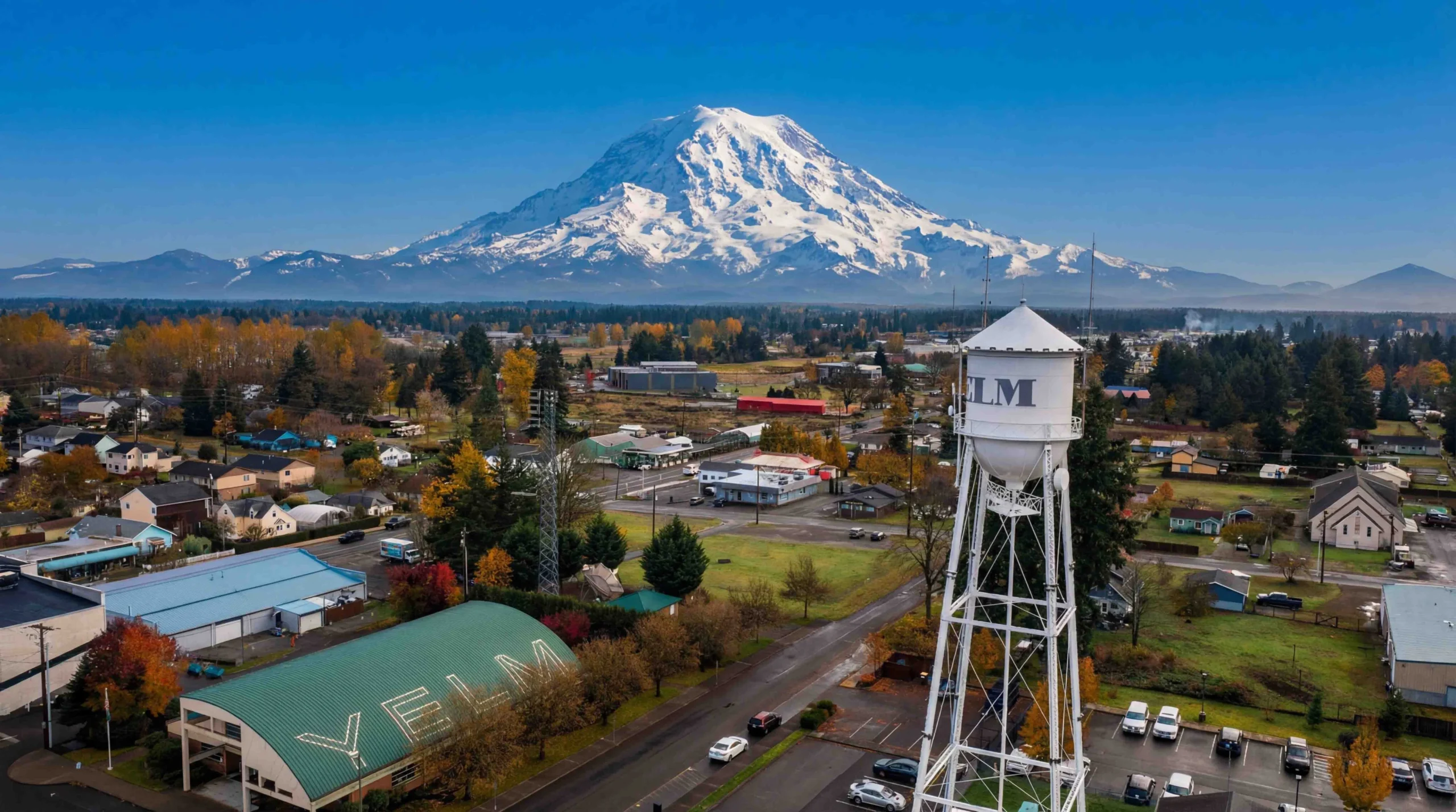 Yelm water tower and town buildings beneath snowy Mount Rainier, where Mayster provides HVAC services in Yelm WA for local homes