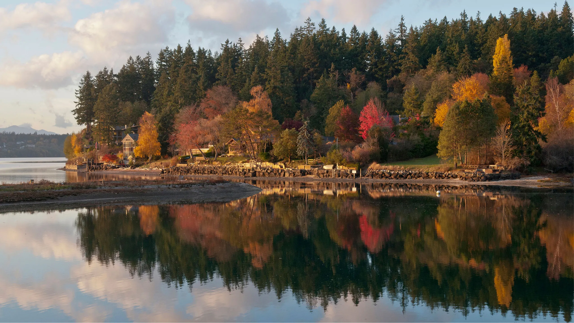 Autumn trees reflected in calm water along the Bainbridge Island shoreline, where Mayster offers HVAC services in Bainbridge Island WA for island homes