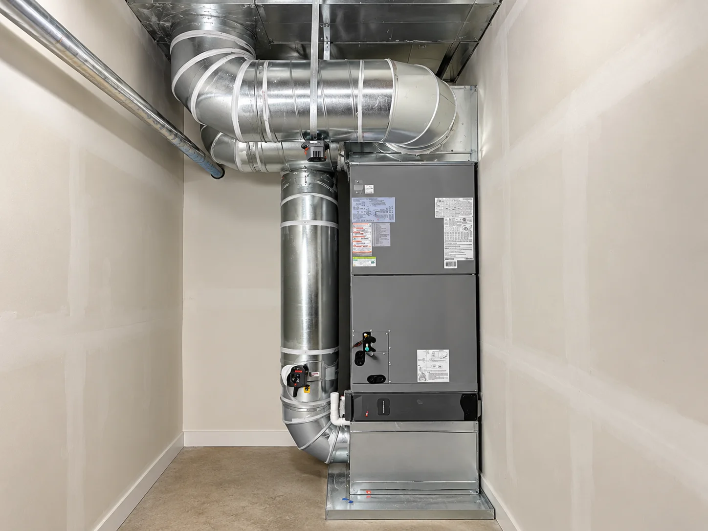 Large gray HVAC unit connected to extensive metal ductwork in a utility room, finished as part of an air handler installation Greater Puget Sound.