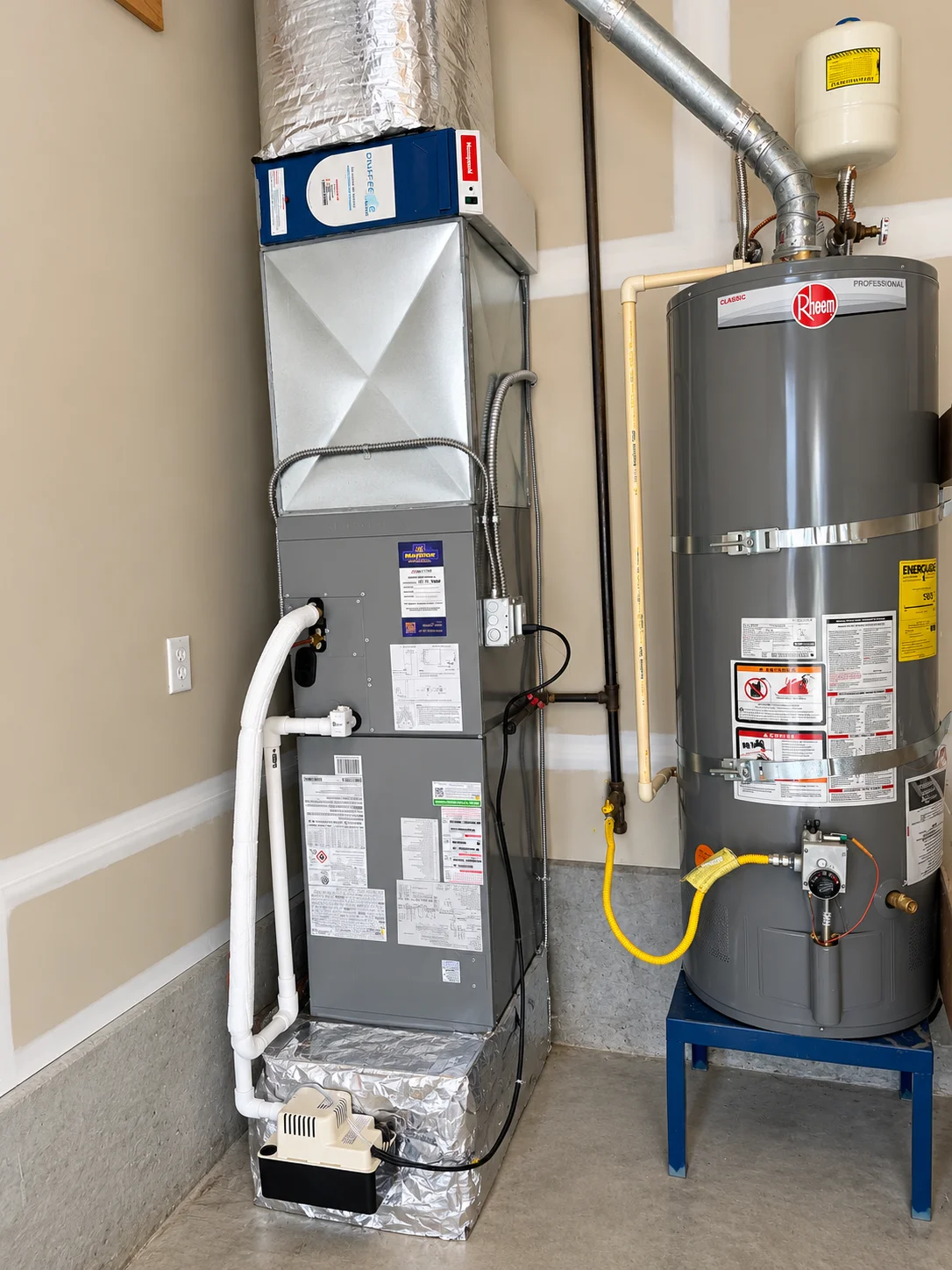 Vertical gray HVAC system next to a Rheem water heater on a stand during an air handler installation Greater Puget Sound.